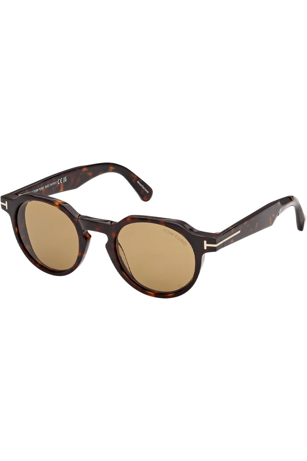 Rotated view of Tom Ford oval sunglasses in yellow with dark tortoise frame and gold T details, shown against a plaid white background.