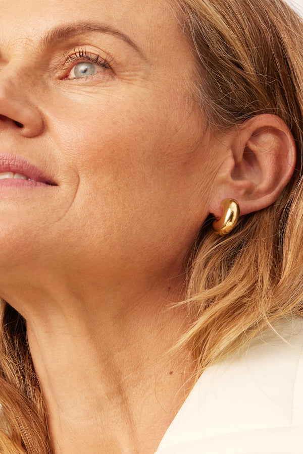 Model wearing the Tome medium hoop earrings in gold colour from the brand JENNY BIRD